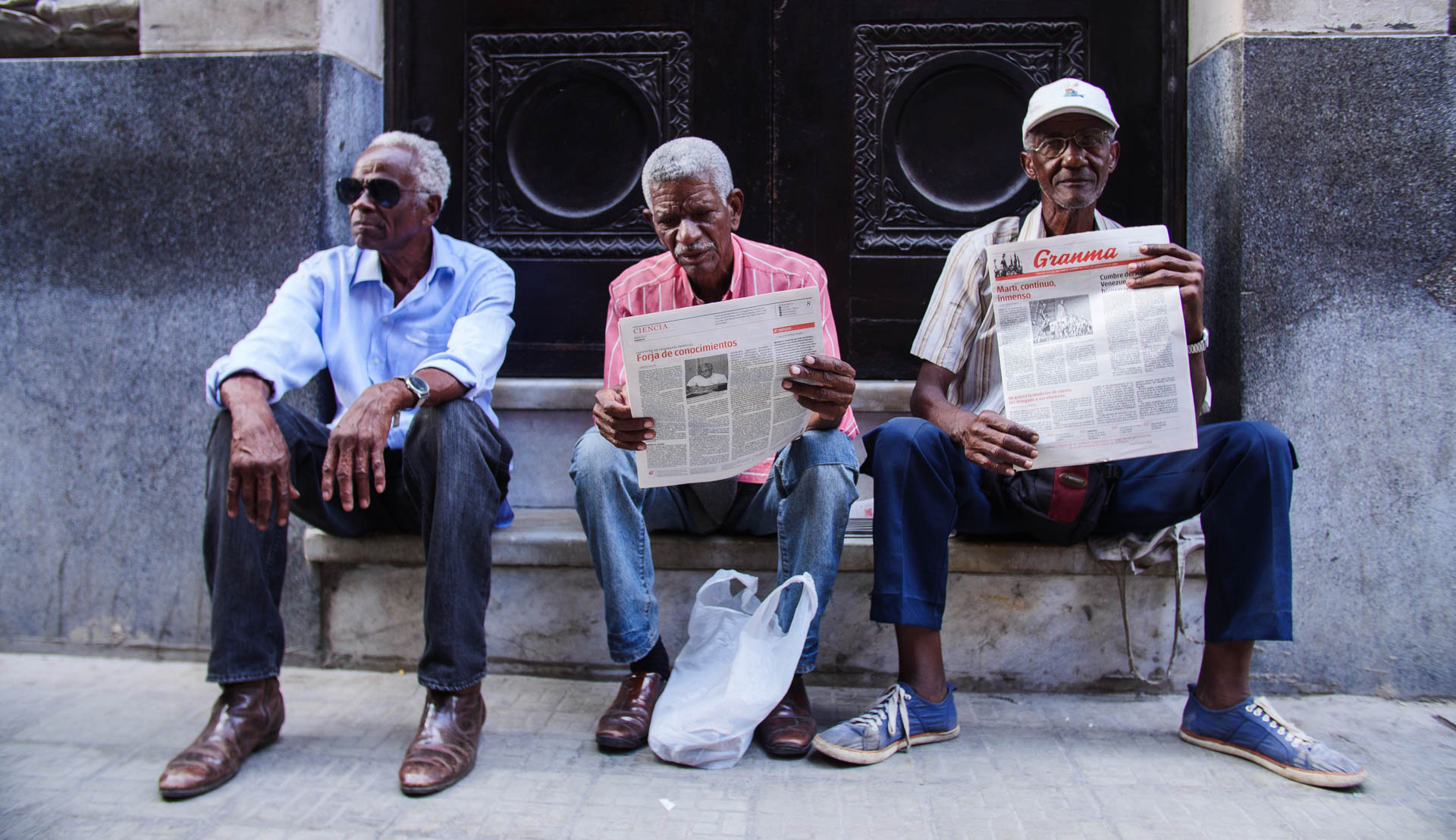 Three men sitting together with newspapers