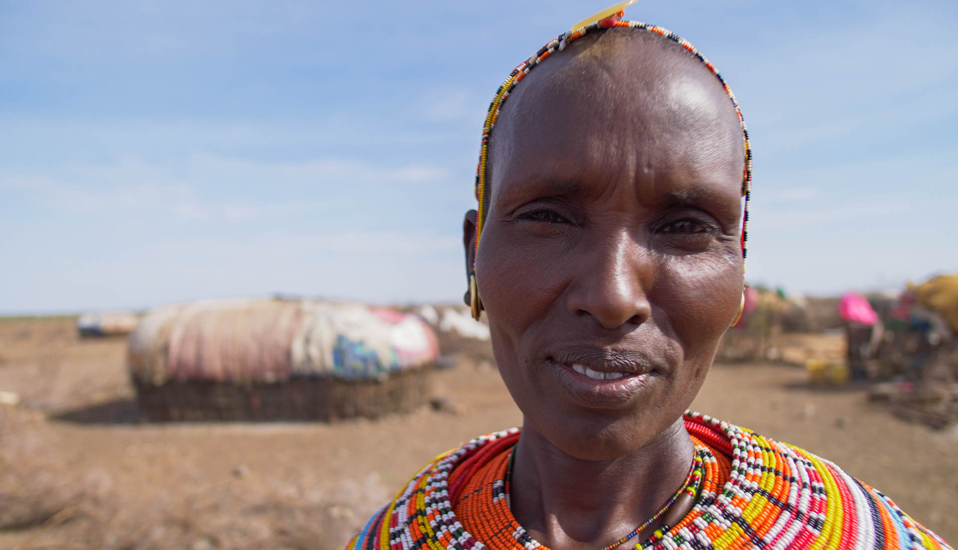 A woman wearing colourful beadwork outside her home